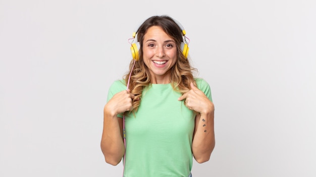 Mulher bonita e magra se sentindo feliz e apontando para si mesma ao som de uma música animada com fones de ouvido