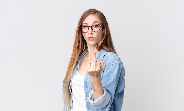 Mulher bonita e magra se sentindo zangada, irritada, rebelde e agressiva, sacudindo o dedo do meio e lutando contra