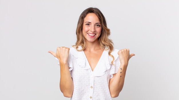 Mulher bonita e magra sorrindo alegremente e parecendo feliz, sentindo-se despreocupada e positiva com os dois polegares para cima