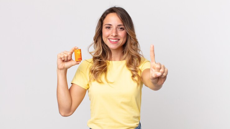 Foto mulher bonita e magra sorrindo e parecendo amigável, mostrando o número um e segurando baterias