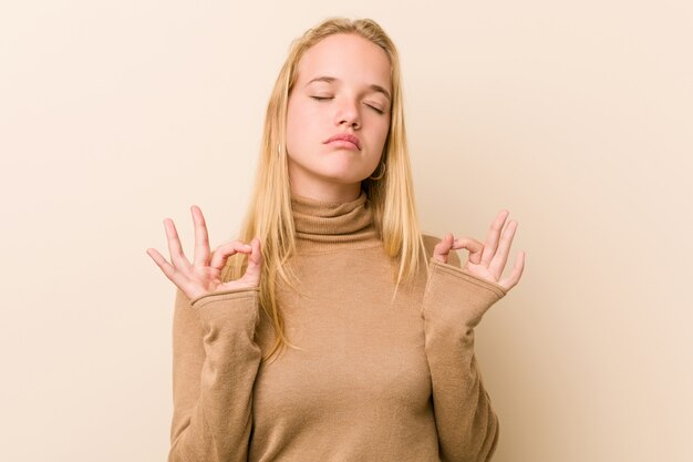 Mulher bonita e natural adolescente relaxa após um duro dia de trabalho, ela está realizando ioga.