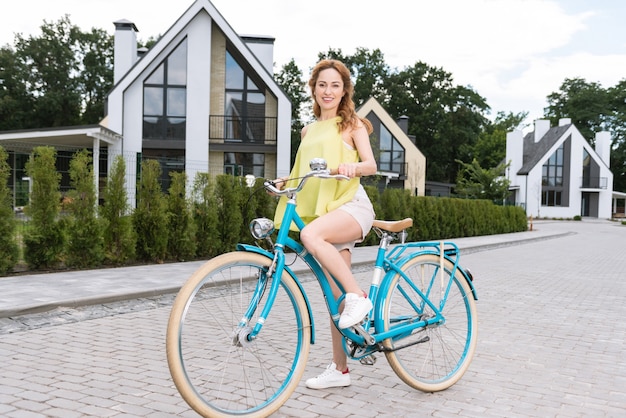 Mulher bonita e simpática sorrindo para você enquanto se prepara para andar de bicicleta