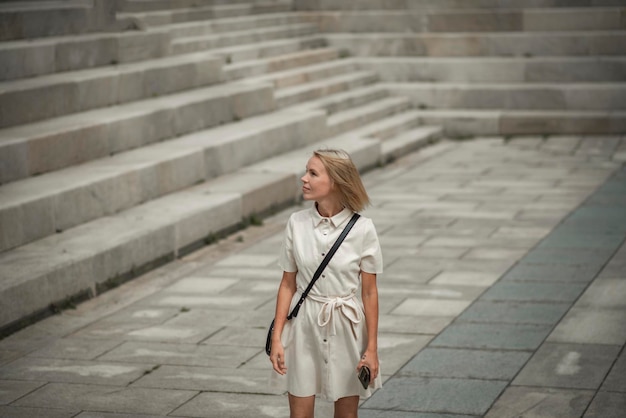 Mulher bonita elegante de 42 anos que parece mais jovem do que sua idade na rua em um vestido branco