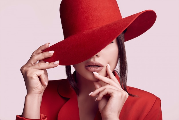 Mulher bonita elegante em um terno vermelho elegante e chapéu largo