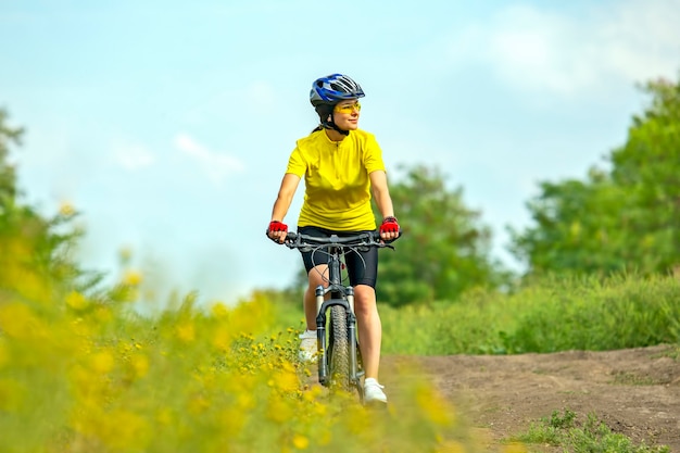 Mulher bonita em amarelo andando de bicicleta na natureza
