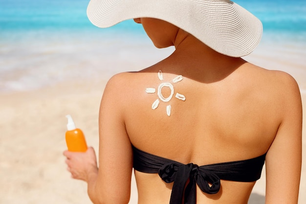 Mulher bonita em biquíni aplicando creme solar no ombro bronzeado proteção solar pele e cuidados com o corpo