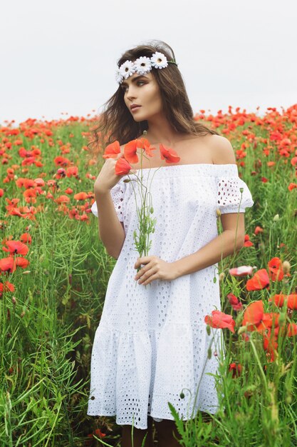 Mulher bonita em campo com muitas flores de papoula