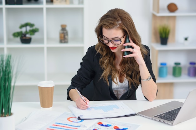 Mulher bonita em copos tendo conversa telefônica de negócios