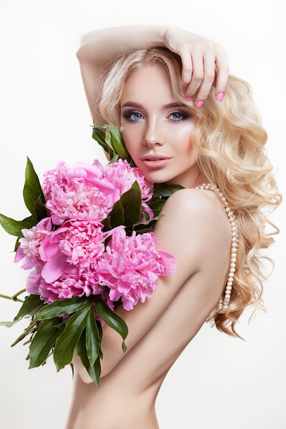 Mulher bonita em fundo branco segurando um buquê de peônias de flores rosa