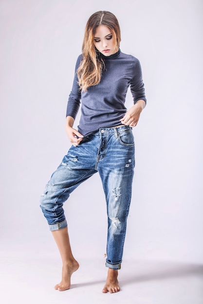 Mulher bonita em jeans e jaqueta. Modelo com roupas da moda com maquiagem em uma superfície leve