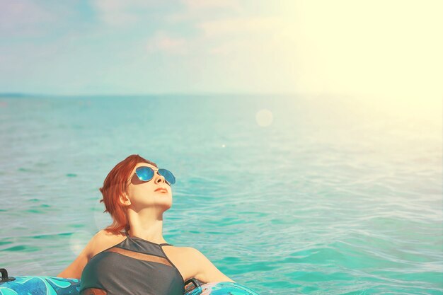 Mulher bonita em óculos de sol relaxar no anel inflável no oceano
