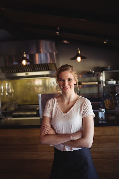 Mulher bonita em pé com os braços cruzados em restaurante