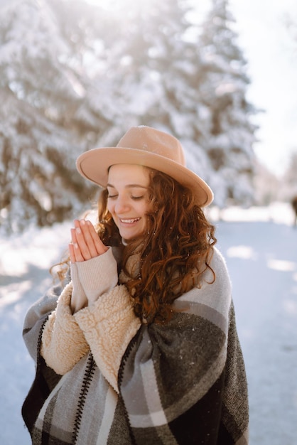 Mulher bonita em pé entre árvores nevadas e curtindo a primeira neve. Tempo feliz. Natal.