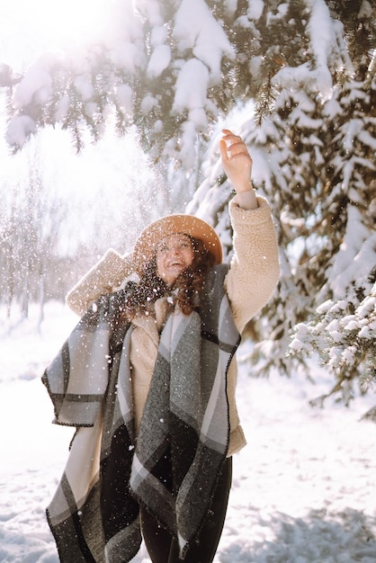 Mulher bonita em pé entre árvores nevadas e curtindo a primeira neve. Tempo feliz. Natal.