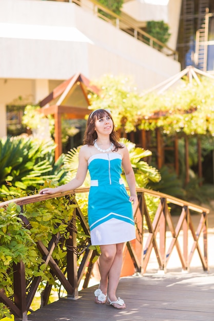 Mulher bonita em roupa de verão posando em resort de luxo. Clima de férias de férias. Vestido azul brilhante.