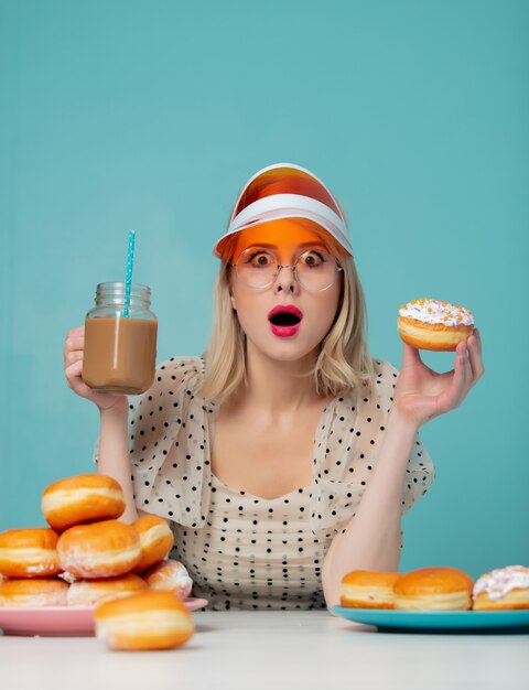 Mulher bonita em roupas dos anos 90 com donuts e café