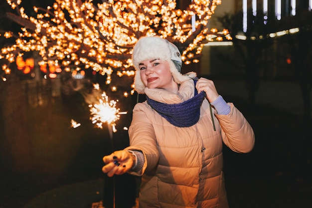 Mulher bonita em um chapéu de malha e lenço em pé na cidade com um diamante. Conceito de celebração e Natal.