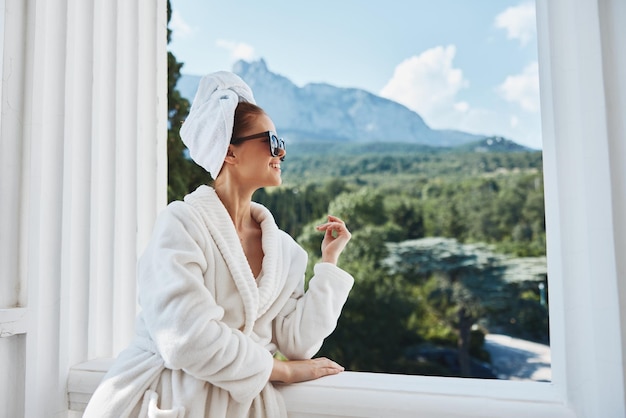 Mulher bonita em um manto branco na varanda pouco no conceito de relaxamento da natureza verde