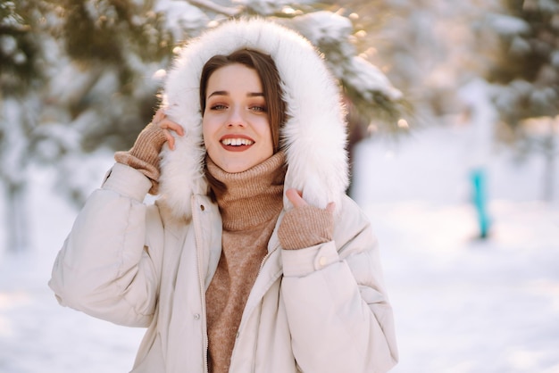 Mulher bonita em um parque nevado. Jovem caminhando em um dia ensolarado de inverno