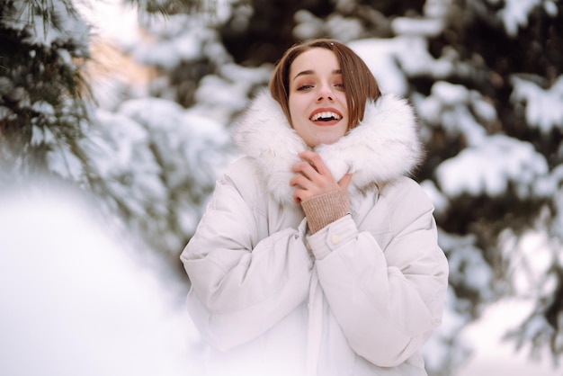 Mulher bonita em um parque nevado. Jovem caminhando em um dia ensolarado de inverno