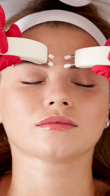 Foto mulher bonita em uma clínica de spa recebendo tratamento facial elétrico estimulante de um terapeuta de perto