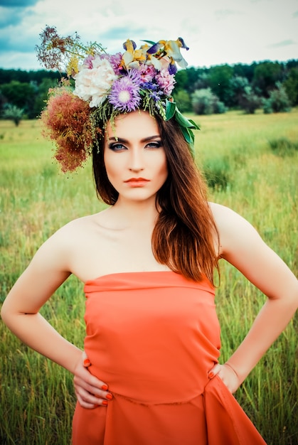 Mulher bonita em uma grinalda de flores na natureza