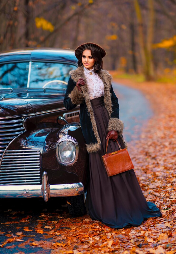 Foto mulher bonita em vestido vintage, blusa de renda e chapéu com véu em pé perto de carro marrom retrô