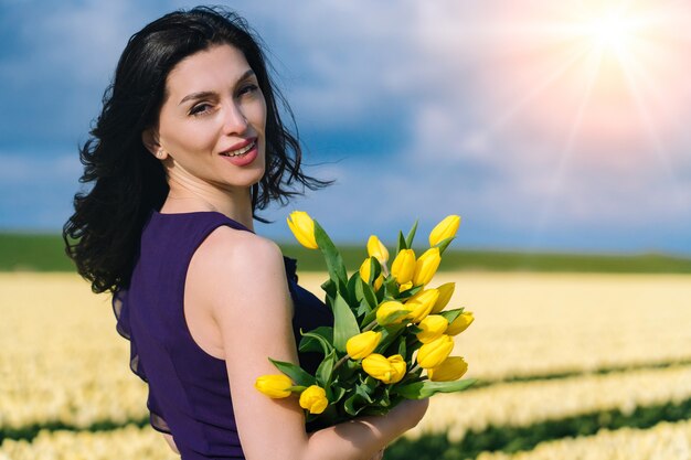 Mulher bonita em vestidos de verão em campos de flores de tulipas coloridas