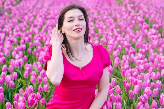 Mulher bonita em vestidos de verão em campos de flores de tulipas coloridas
