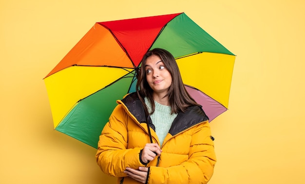 Mulher bonita encolhendo os ombros sentindo-se confuso e incerto inverno e conceito de guarda-chuva