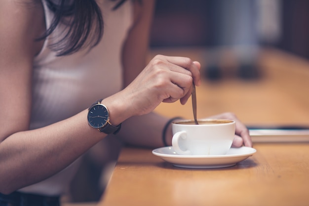 Mulher bonita, escrevendo a mensagem de texto no telefone inteligente em um café