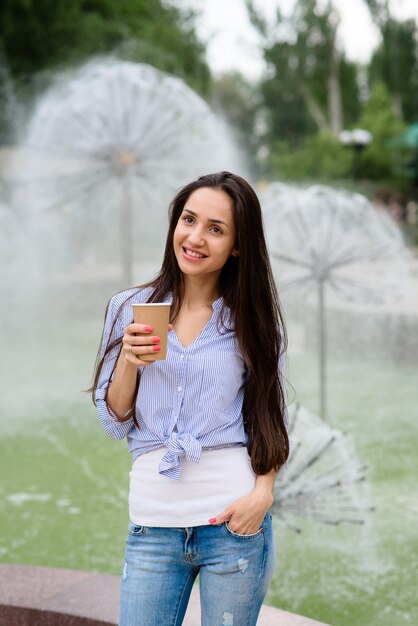 Mulher bonita está bebendo café em um café de rua.