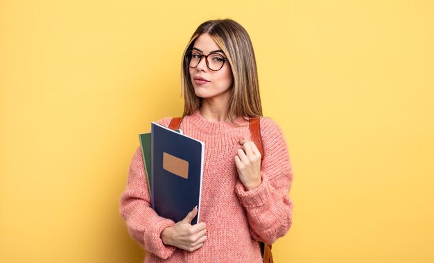 Mulher bonita estudante olhando arrogante, bem sucedida, positiva e orgulhosa. livros e mochila