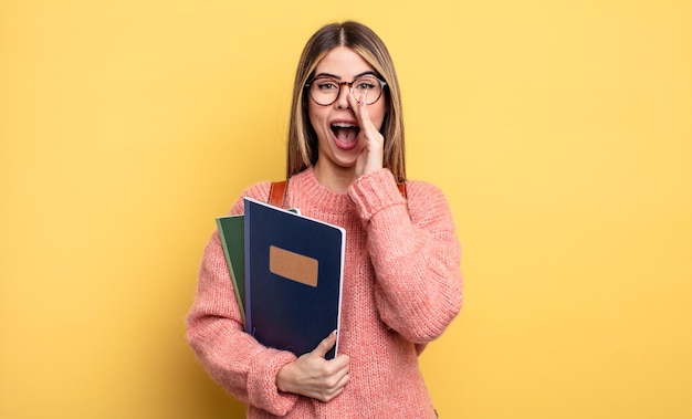 Mulher bonita estudante se sentindo feliz, dando um grande grito com as mãos ao lado da boca. livros e mochila