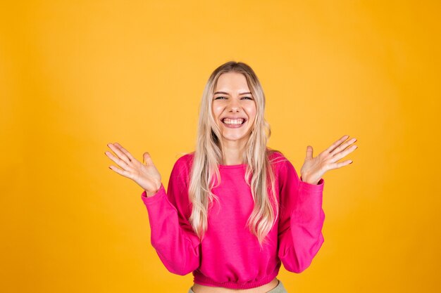 Mulher bonita europeia com blusa rosa na parede amarela