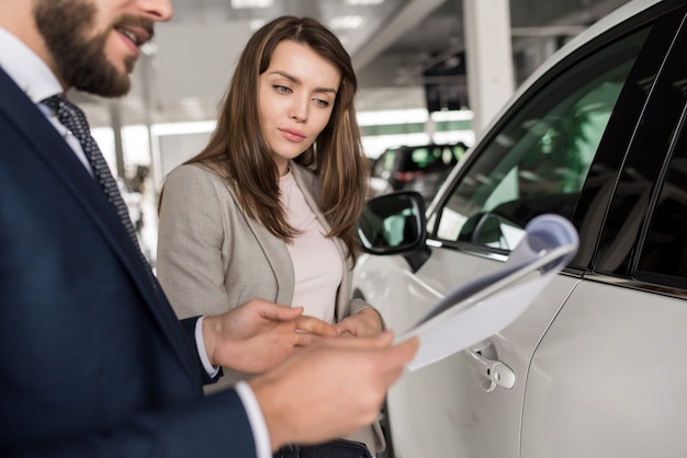 Mulher bonita falando com vendedor de carros