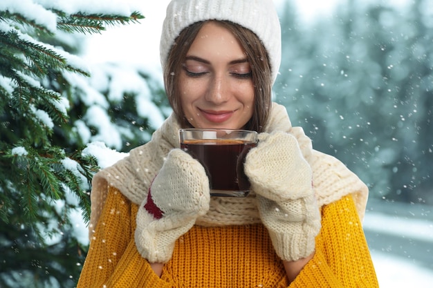 Mulher bonita feliz com vinho quente ao ar livre em dia de neve