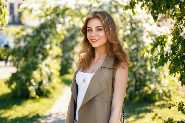 Mulher bonita feliz em roupas de grife posando no parque em um dia ensolarado