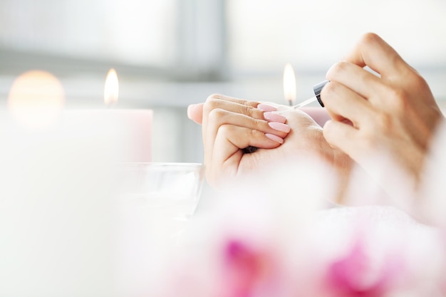 Mulher bonita feliz fazendo manicure enquanto descansava em casa.