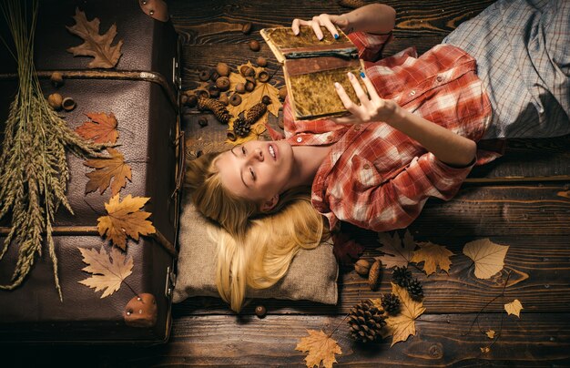 Mulher bonita feliz lendo livro nas folhas amarelas de outono