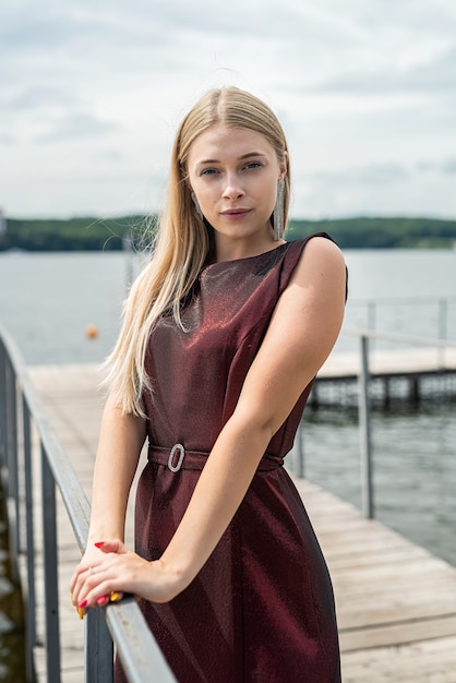 Mulher bonita fica com um vestido vermelho escuro longo na natureza. Conceito de viagens.