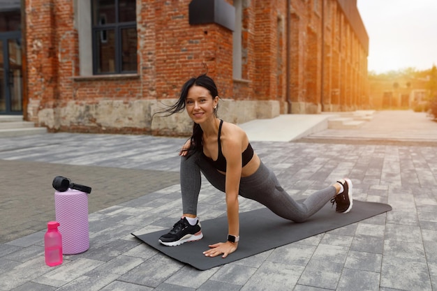 Mulher bonita fitness fazendo exercícios de alongamento na rua