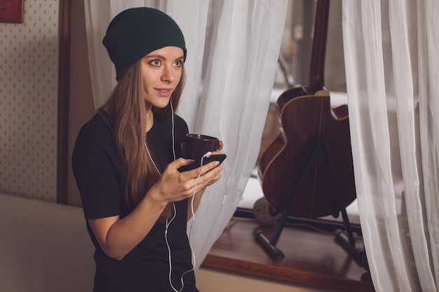 Mulher bonita hipster ouvindo música perto de guitarra