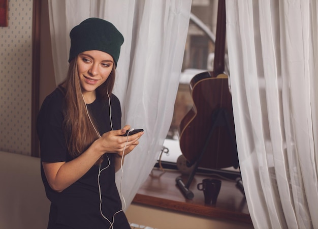 Mulher bonita hipster ouvindo música perto de guitarra