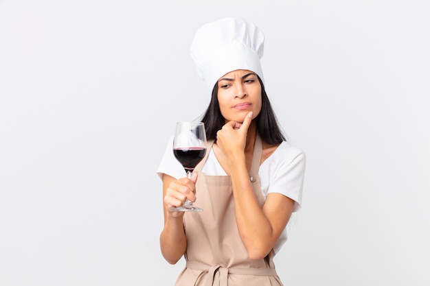 Mulher bonita hispânica chef segurando uma taça de vinho