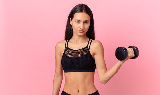 Mulher bonita hispânica com um haltere. conceito de fitness