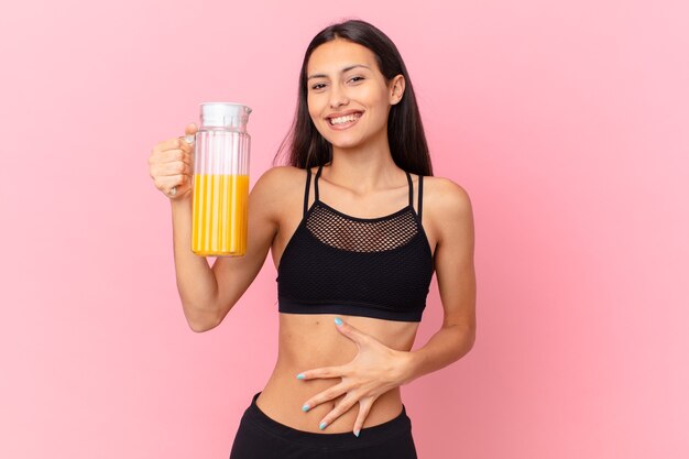 Mulher bonita hispânica fitness com um suco de laranja