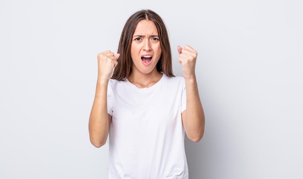 Mulher bonita hispânica gritando agressivamente com uma expressão de raiva ou com os punhos cerrados comemorando o sucesso