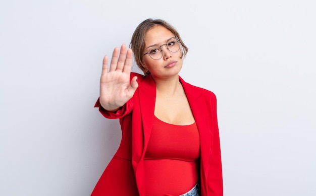 Mulher bonita hispânica olhando séria mostrando a palma da mão aberta, fazendo gesto de parada. Concetp de empresária