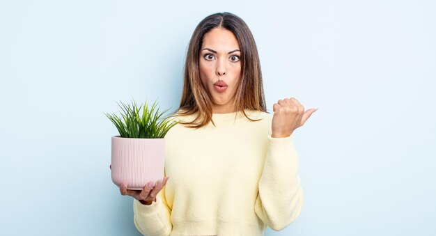 Mulher bonita hispânica parecendo espantada com a descrença. conceito de planta de casa